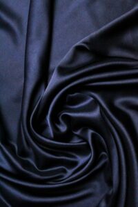 Close-up of luxurious black satin fabric with a swirling texture, perfect for fashion and design uses.